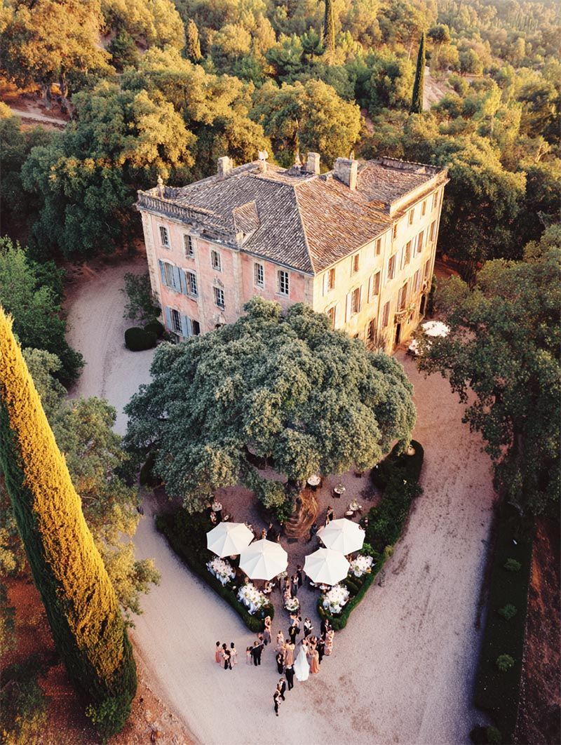 Aerial view of a French château destination wedding ceremony set in formal gardens framed by cypress trees