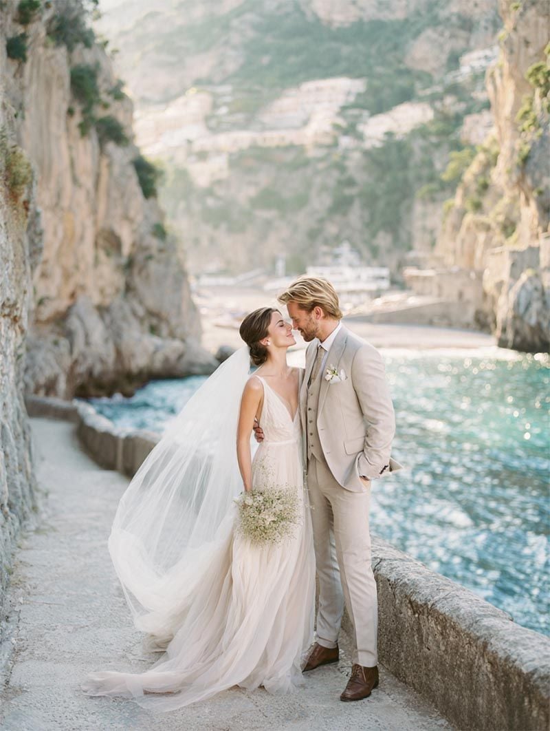 Bride and groom at a luxury wedding destination, cliffside overlooking a large body of water